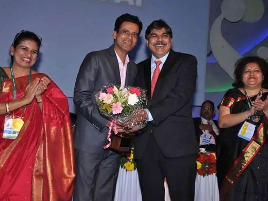 Dr. Hrishikesh Pai being felicitated with flowers and a trophy on stage